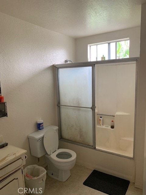 full bathroom featuring a textured ceiling, combined bath / shower with glass door, vanity, and toilet