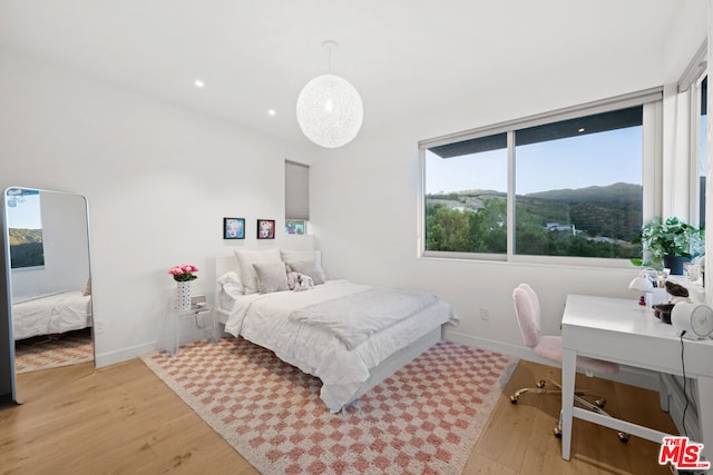 bedroom with a mountain view and light wood-type flooring