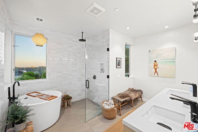 bathroom featuring independent shower and bath, tile patterned flooring, vanity, and tile walls