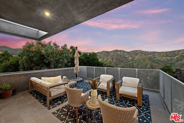 patio terrace at dusk with outdoor lounge area and a mountain view