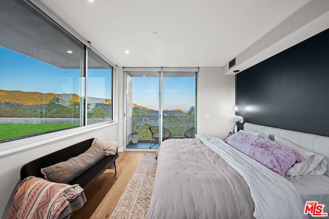 bedroom with access to outside, a wall of windows, and light hardwood / wood-style floors