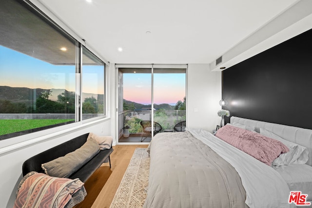 bedroom featuring a wall of windows, light hardwood / wood-style flooring, and access to exterior