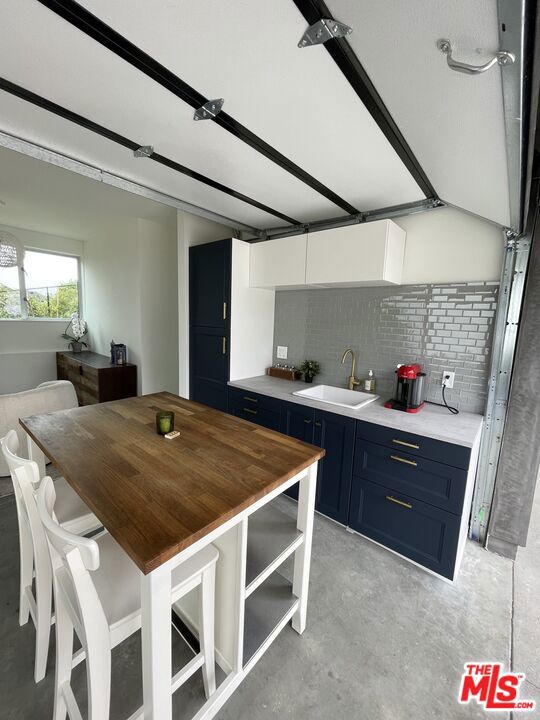 kitchen featuring sink, white cabinetry, butcher block counters, decorative backsplash, and blue cabinets