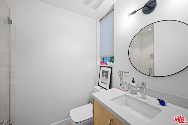 bathroom with vanity, a shower with shower door, and toilet