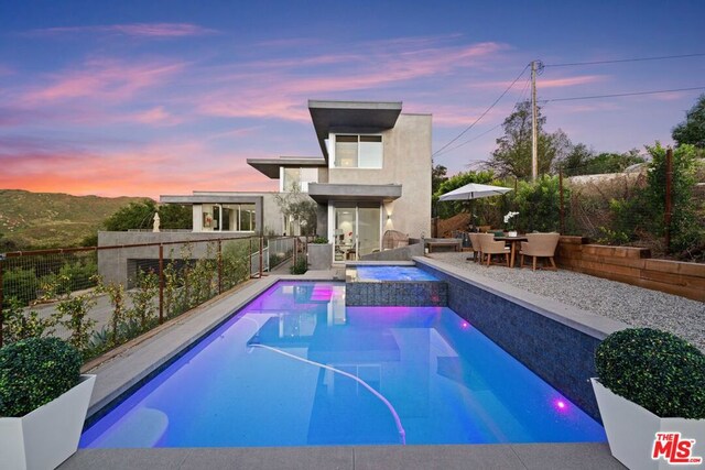 pool at dusk featuring a patio area