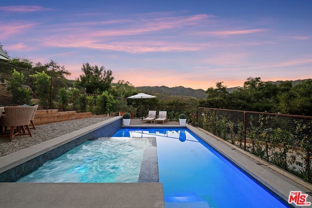 pool at dusk featuring a patio