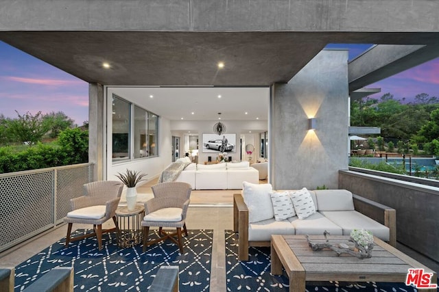 patio terrace at dusk with a balcony and an outdoor living space