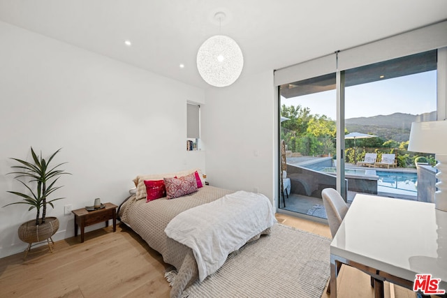 bedroom featuring access to outside, light hardwood / wood-style floors, and a mountain view