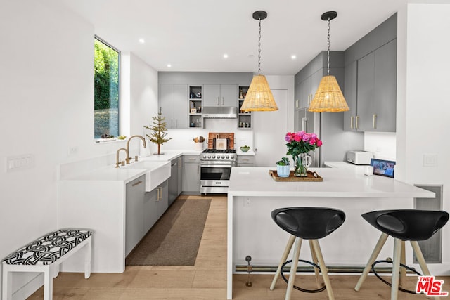 kitchen with appliances with stainless steel finishes, a kitchen breakfast bar, and gray cabinetry