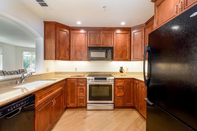 kitchen featuring light stone countertops, black appliances, sink, kitchen peninsula, and light hardwood / wood-style flooring