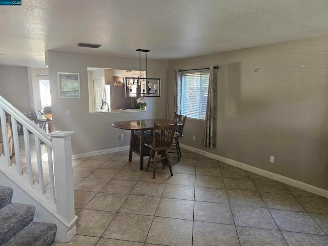 dining space with a notable chandelier, a textured ceiling, and light tile patterned floors