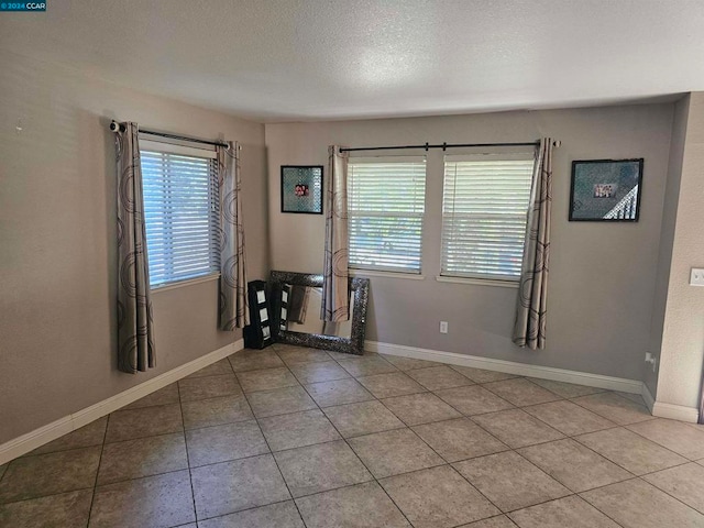 tiled spare room with a textured ceiling and plenty of natural light