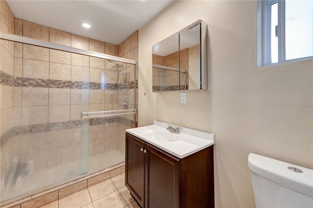 bathroom featuring tile patterned flooring, vanity, an enclosed shower, and toilet