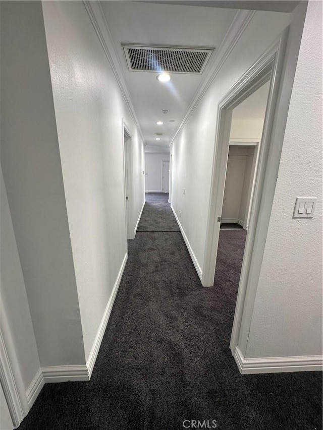 hallway featuring dark carpet and ornamental molding