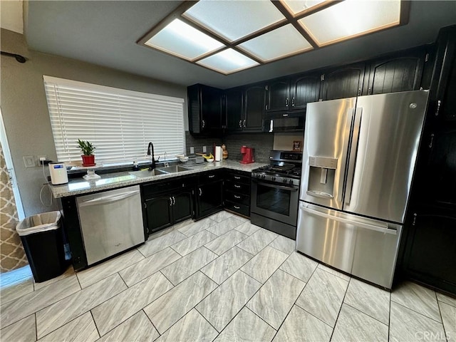 kitchen featuring backsplash, sink, range hood, light stone counters, and stainless steel appliances