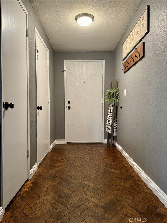 hallway featuring dark parquet flooring and a textured ceiling