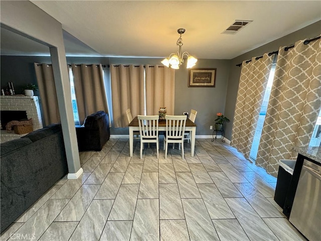 dining space featuring a notable chandelier and a brick fireplace