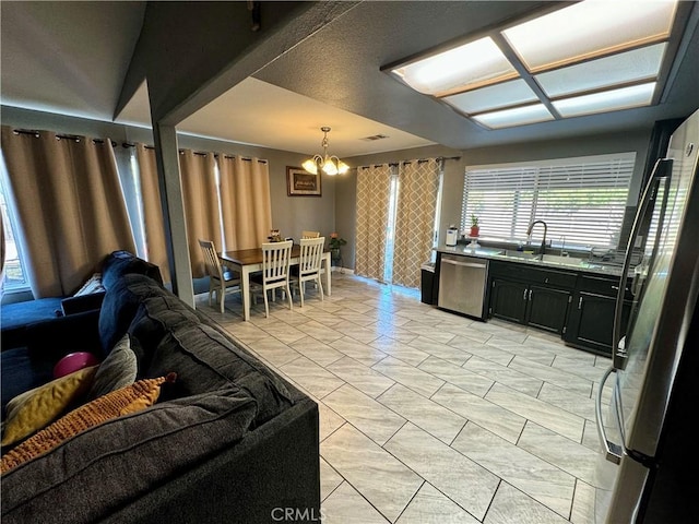 kitchen with sink, hanging light fixtures, stainless steel appliances, an inviting chandelier, and light tile patterned floors