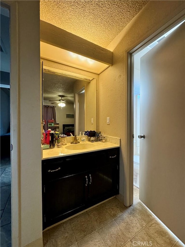 bathroom with ceiling fan, tile patterned floors, a textured ceiling, toilet, and vanity