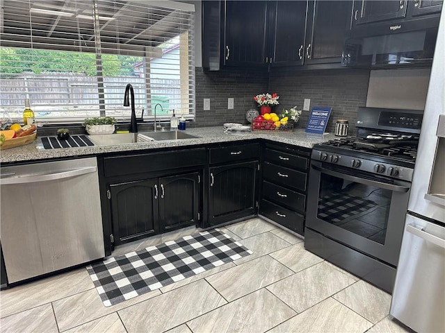 kitchen with light stone countertops, backsplash, stainless steel appliances, and sink