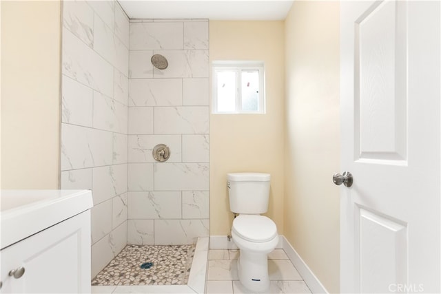 bathroom featuring a tile shower, vanity, and toilet