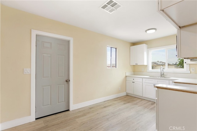 kitchen featuring light hardwood / wood-style floors, white cabinetry, and sink