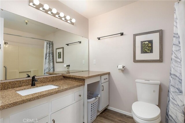 bathroom featuring walk in shower, hardwood / wood-style flooring, vanity, and toilet