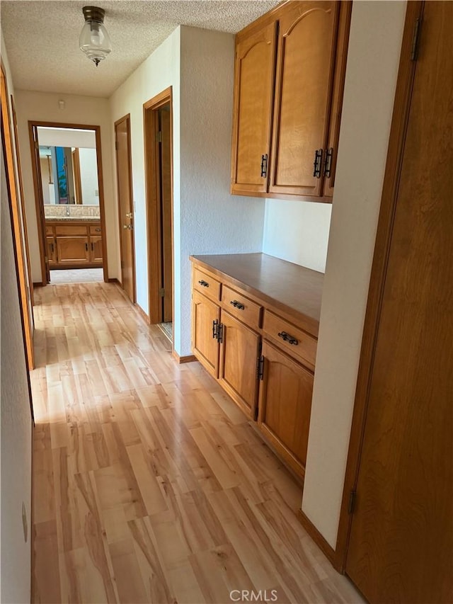 corridor featuring light hardwood / wood-style floors and a textured ceiling