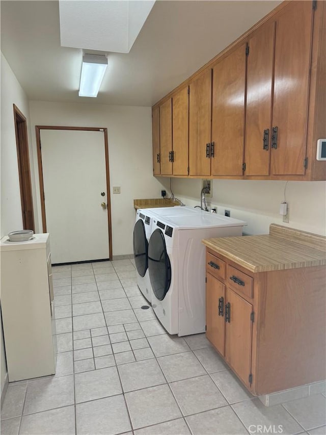 laundry area with cabinets, light tile patterned flooring, and washing machine and clothes dryer