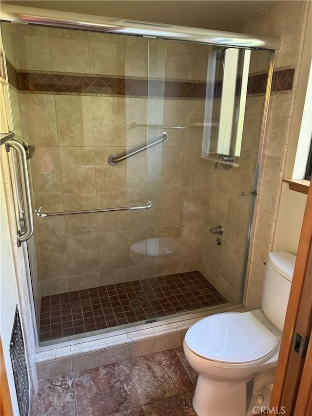 bathroom with a shower with door and toilet