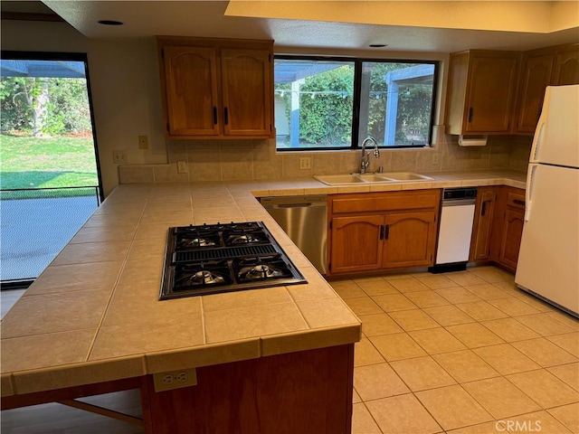 kitchen featuring tile counters, stainless steel appliances, plenty of natural light, and sink