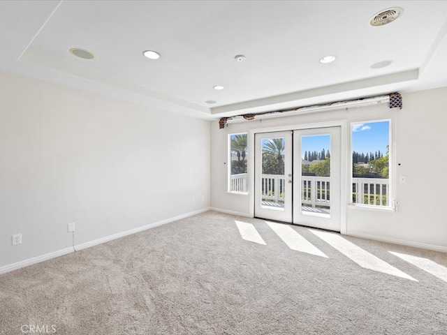 carpeted spare room featuring french doors and a tray ceiling