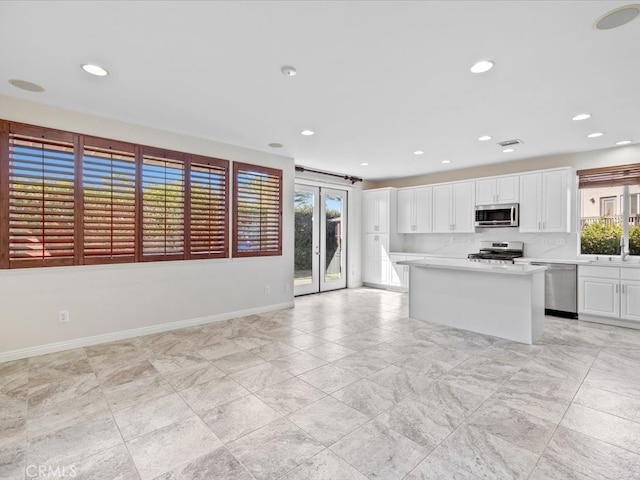 kitchen with stainless steel appliances, a kitchen island, and white cabinetry