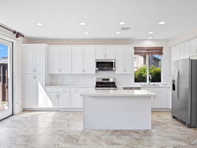 kitchen featuring stainless steel appliances, plenty of natural light, sink, and white cabinetry