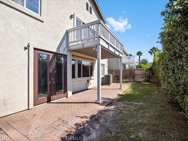 back of house featuring a wooden deck, a patio, central AC unit, and a lawn