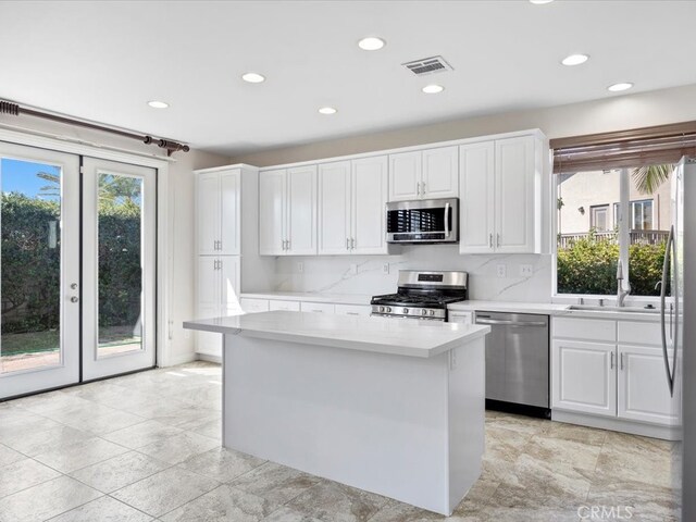 kitchen featuring stainless steel appliances, a wealth of natural light, and white cabinetry