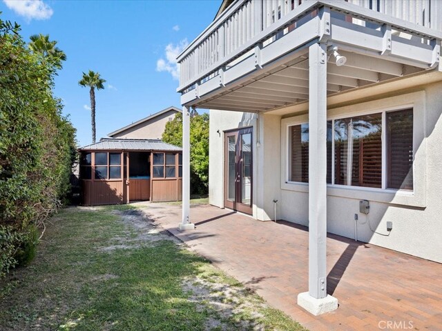 view of patio with a sunroom and a balcony