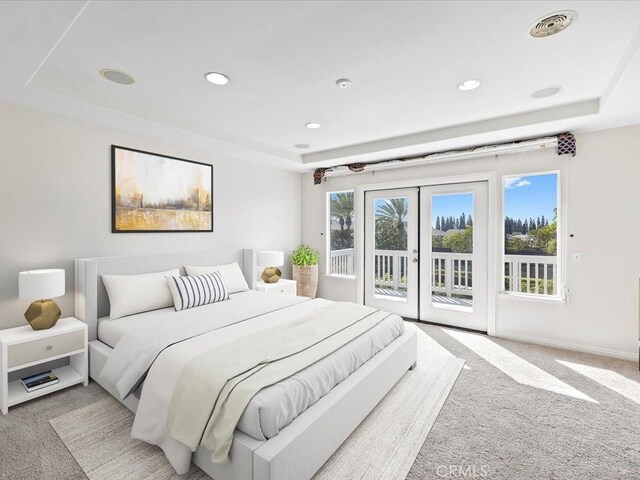 bedroom with a raised ceiling, french doors, access to outside, and carpet