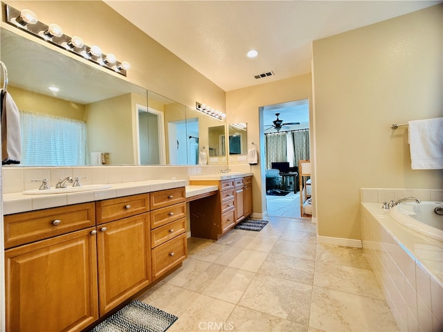 bathroom featuring ceiling fan, tiled bath, and vanity