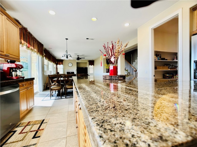 kitchen with stainless steel dishwasher, pendant lighting, light stone countertops, and light tile patterned floors