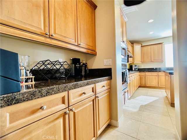 kitchen with light brown cabinets, stainless steel oven, and light tile patterned floors