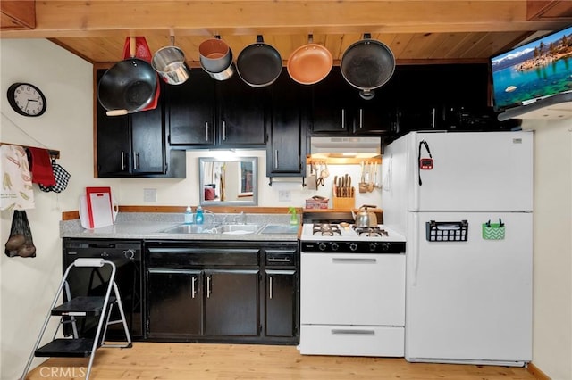 kitchen with exhaust hood, a sink, light wood finished floors, dark cabinetry, and white appliances
