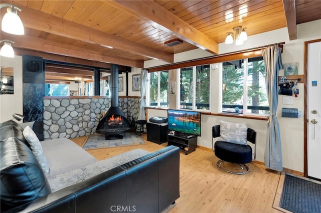 living room with beam ceiling, a wood stove, wooden ceiling, an inviting chandelier, and light hardwood / wood-style flooring