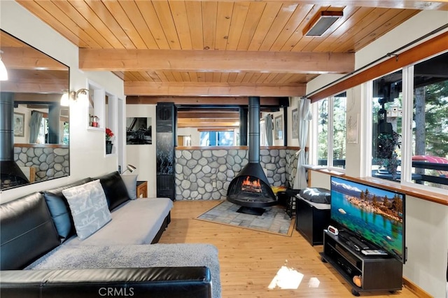 living room featuring beam ceiling, a wood stove, wood ceiling, and light wood-type flooring