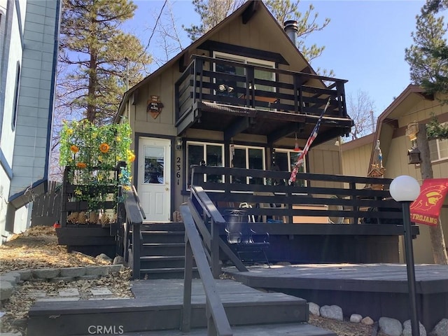 view of front of house with a wooden deck, a balcony, and a chimney