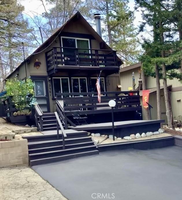 back of house with a wooden deck and a balcony