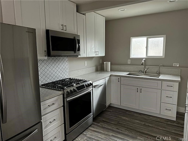 kitchen with white cabinetry, sink, dark wood-type flooring, stainless steel appliances, and decorative backsplash