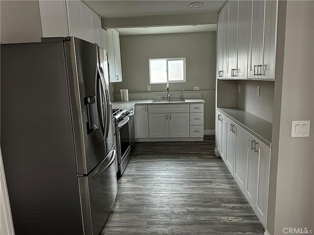 kitchen with sink, kitchen peninsula, dark hardwood / wood-style floors, appliances with stainless steel finishes, and white cabinetry