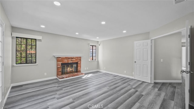 unfurnished living room featuring light hardwood / wood-style floors and a brick fireplace