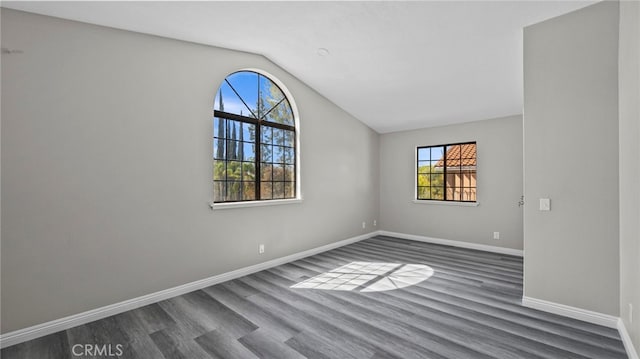 empty room with dark hardwood / wood-style flooring and vaulted ceiling